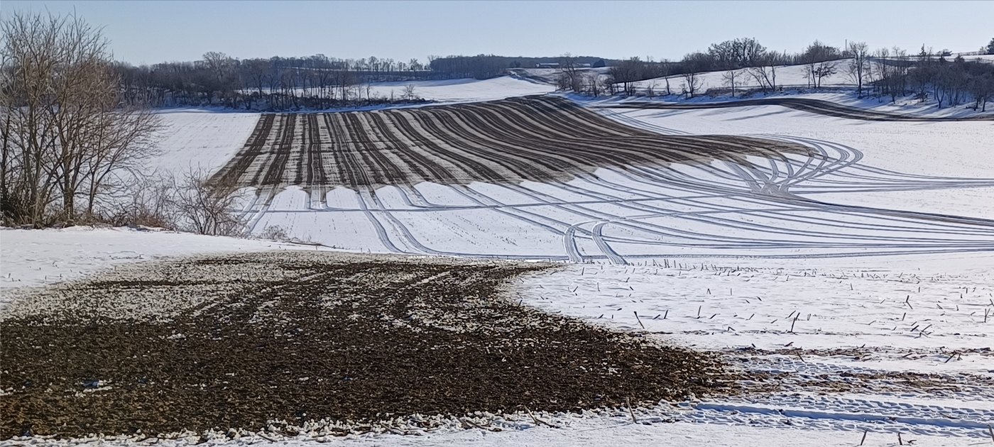 Manure spread in dark streaks across a snow-covered field